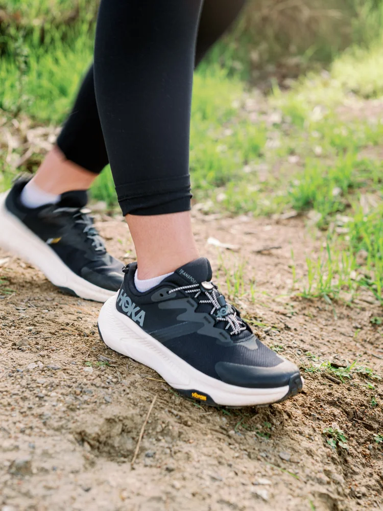 A close-up of running shoes on a dirt trail