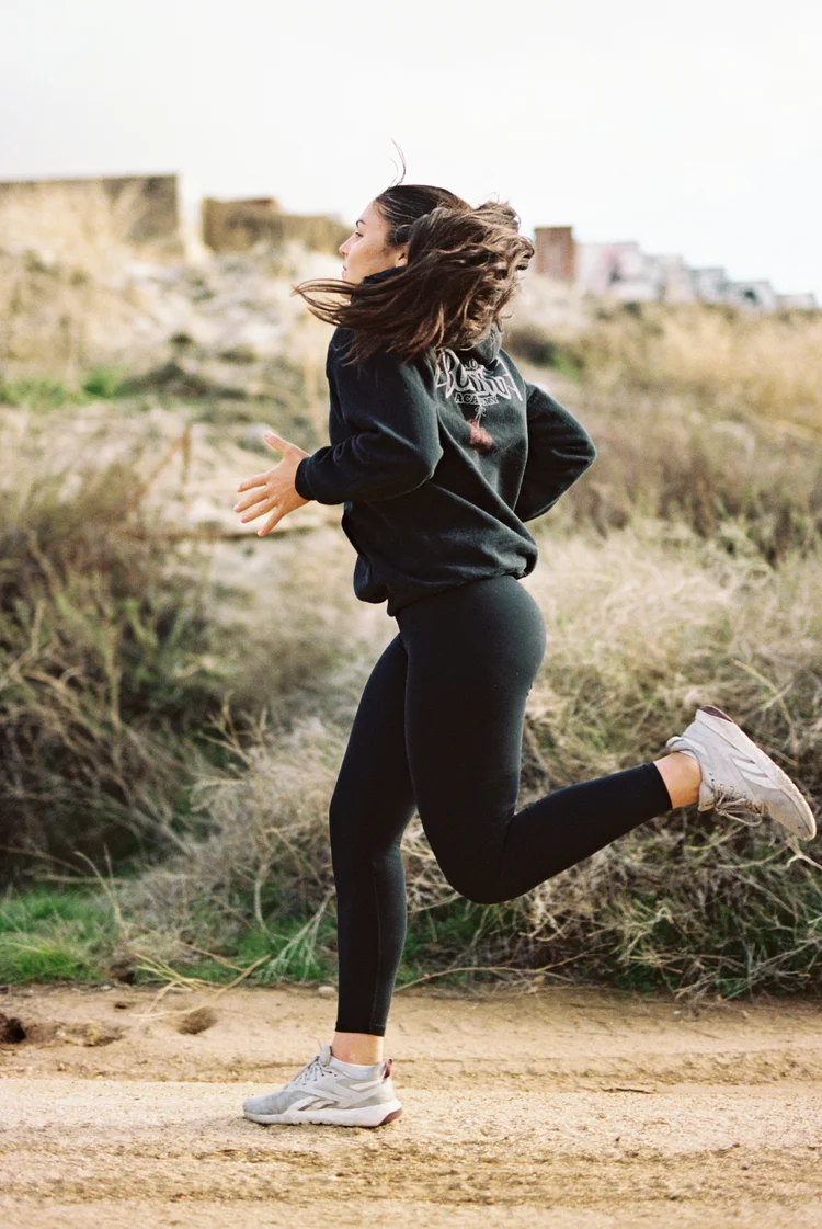 A runner on a trail in a hooded sweatshirt